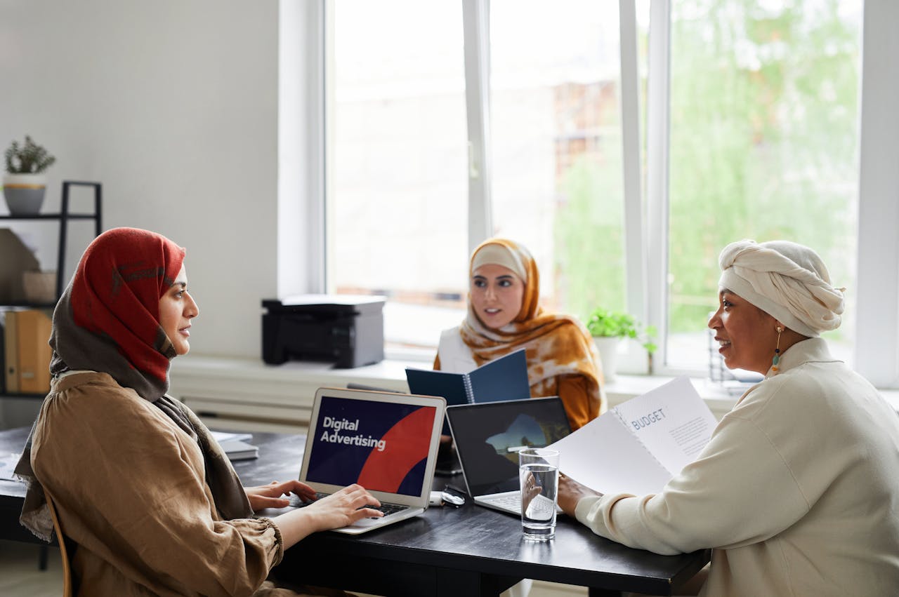 Three businesswomen in a meeting room discussing digital advertising projects.